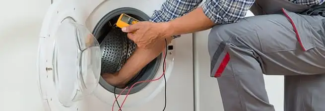 Dryer repair technician inspecting and repairing a clothes dryer in Portland, OR