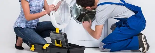 Washer repair technician inspecting a front-load washing machine with tools in Portland, OR