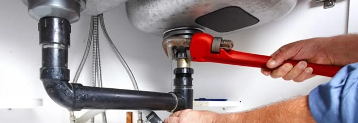 Garbage disposal repair technician tightening the sink drain and disposal connection in Portland, OR