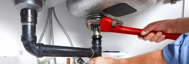 Garbage disposal repair technician tightening the sink drain and disposal connection in Portland, OR