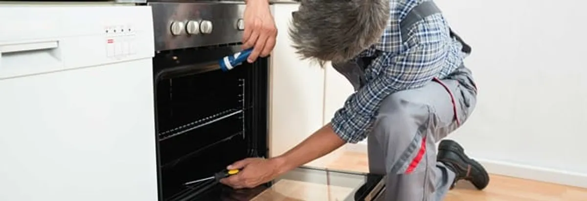 Oven repair technician inspecting and servicing an electric oven in Portland, OR