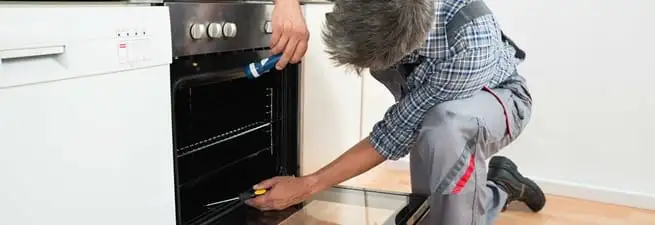 Oven repair technician inspecting and servicing an electric oven in Portland, OR