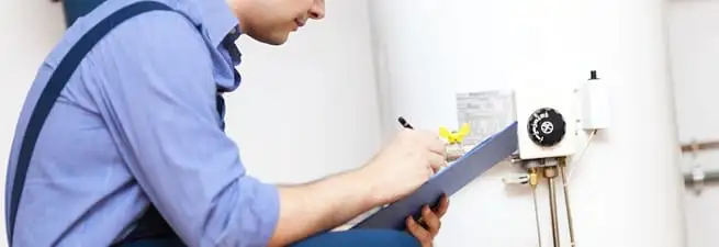 Water heater repair technician inspecting the unit and recording service notes in Portland, OR