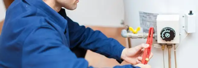 Water heater repair technician adjusting the temperature control and gas valve in Portland, OR